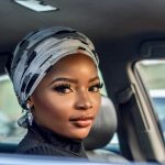 Portrait of a beautiful woman wearing a headscarf sitting inside a car, showcasing elegance and beauty.
