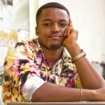 Young man wearing a colorful floral shirt, posing with a thoughtful expression indoors.