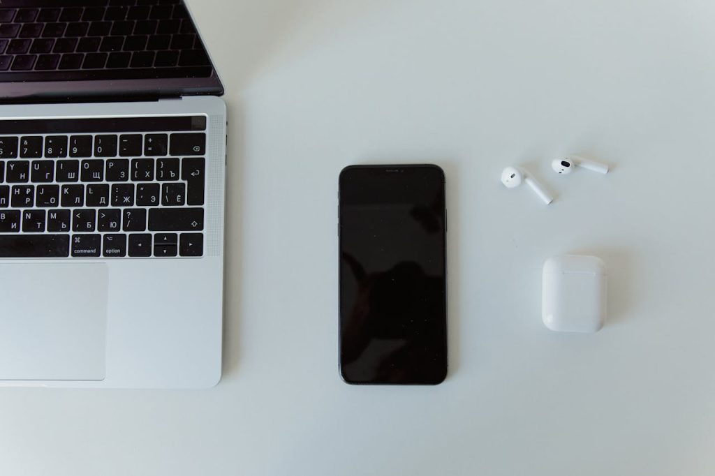 pexels-photo-8004014 Top view of a laptop, smartphone, and wireless earphones on a white desk.